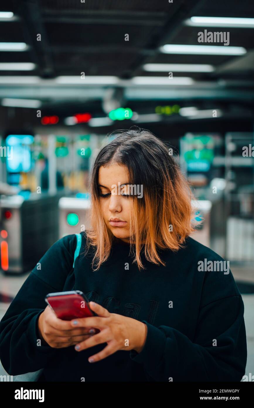 Female student using smart phone at subway during night Stock Photo