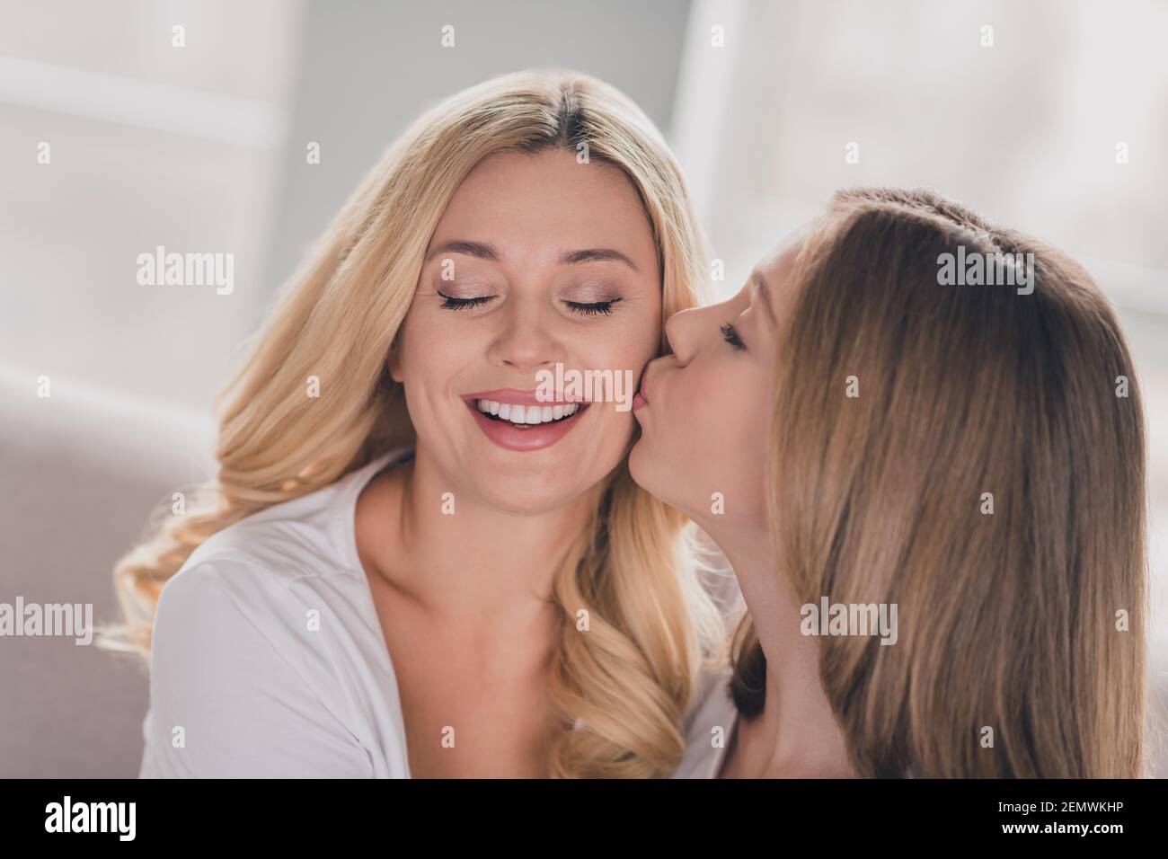 Photo Of Shiny Lovely Daughter Mom Wear White T Shirts Kissing Cheek Cheekbone Hugging Sitting
