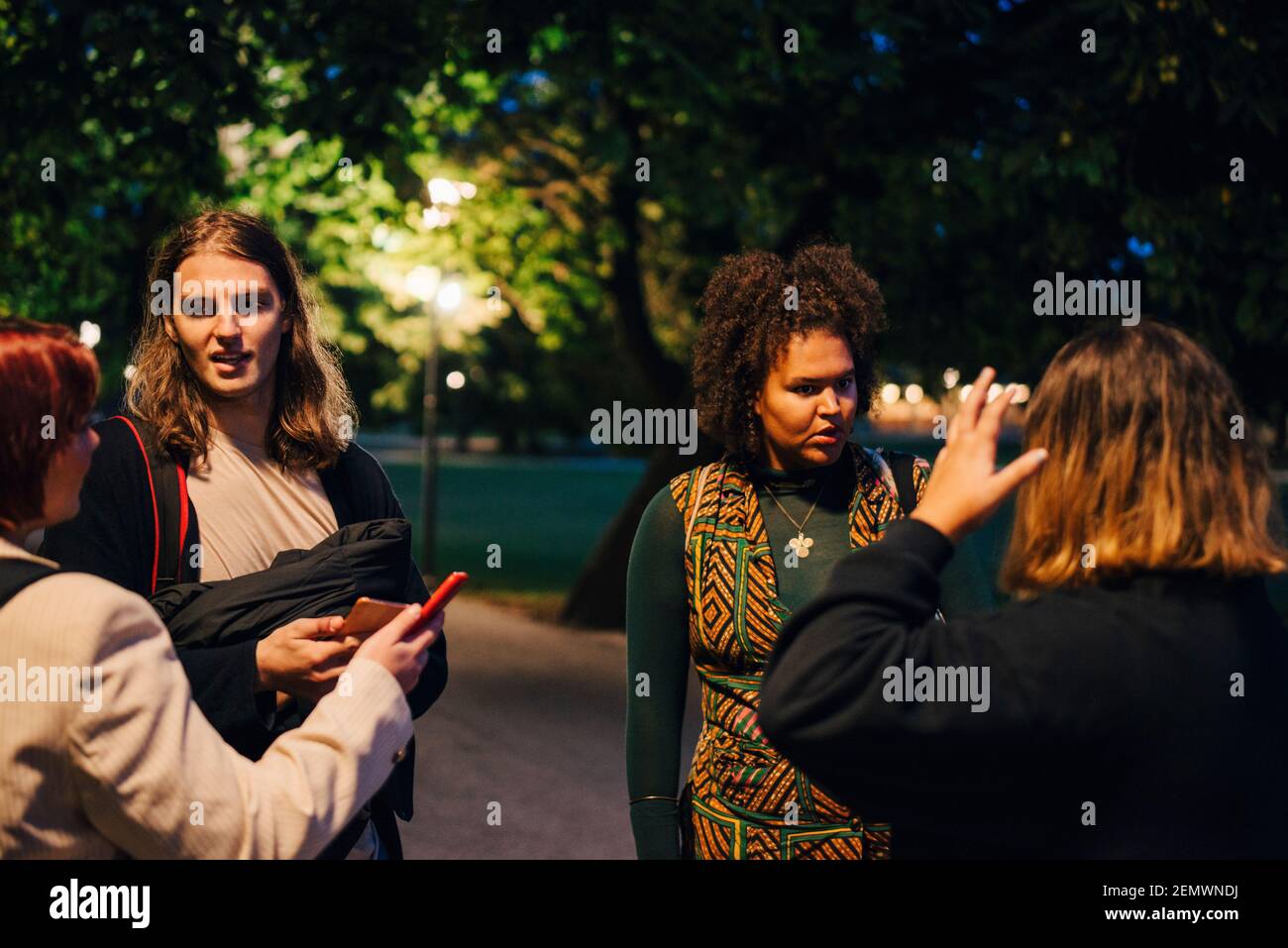 Female and male friends talking with each other in college campus at night Stock Photo
