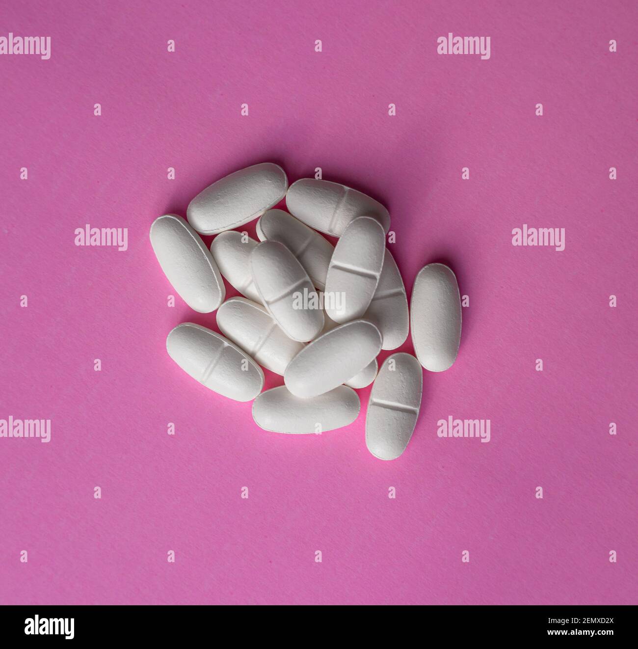 White large pills on a pink background Stock Photo