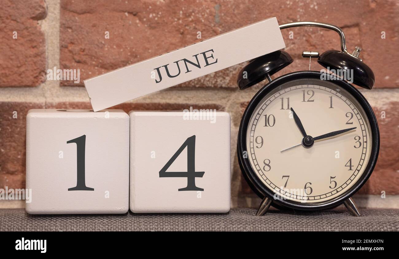 Important date, June 14, summer season. Calendar made of wood on a background of a brick wall. Retro alarm clock as a time management concept. Stock Photo