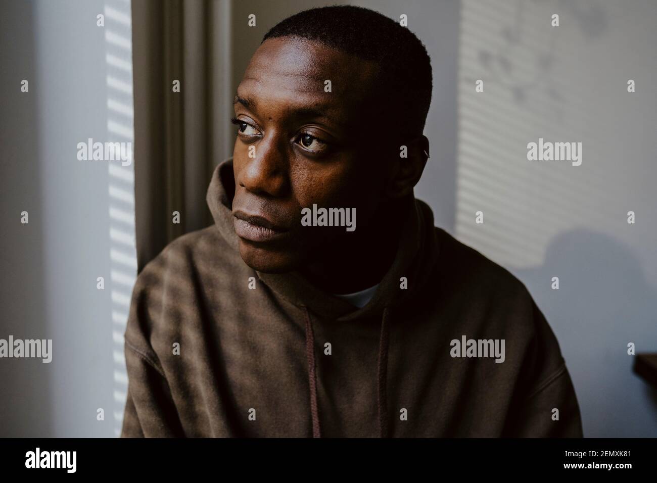 Thoughtful man looking away against wall Stock Photo