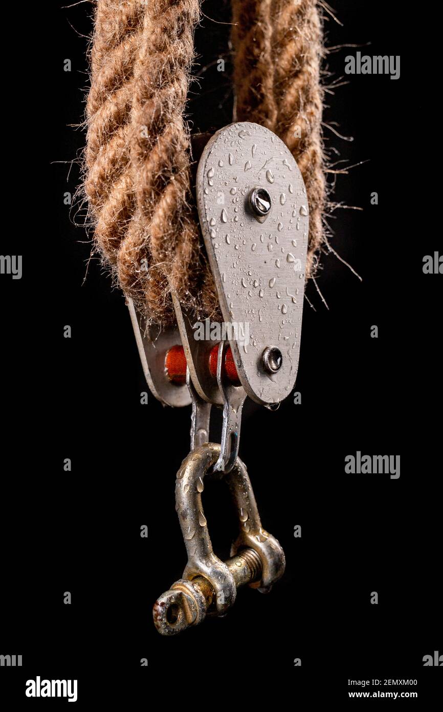 Thick jute rope wrapped on rollers in a sailing pulley. Accessories used on yachts for sailing in the sea. Dark background. Stock Photo