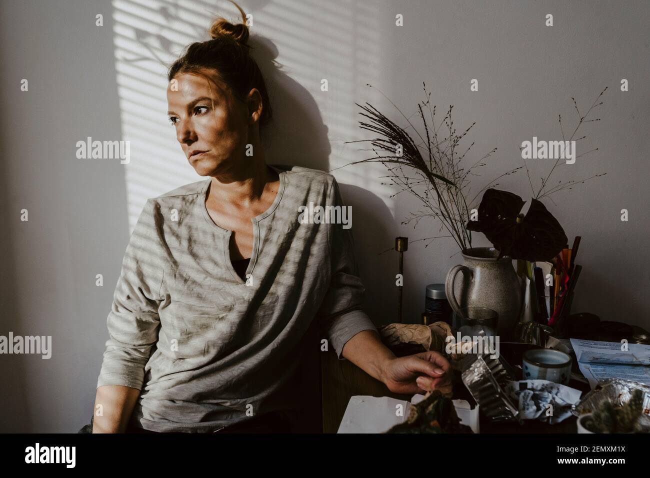 Thoughtful woman looking away against wall at home Stock Photo
