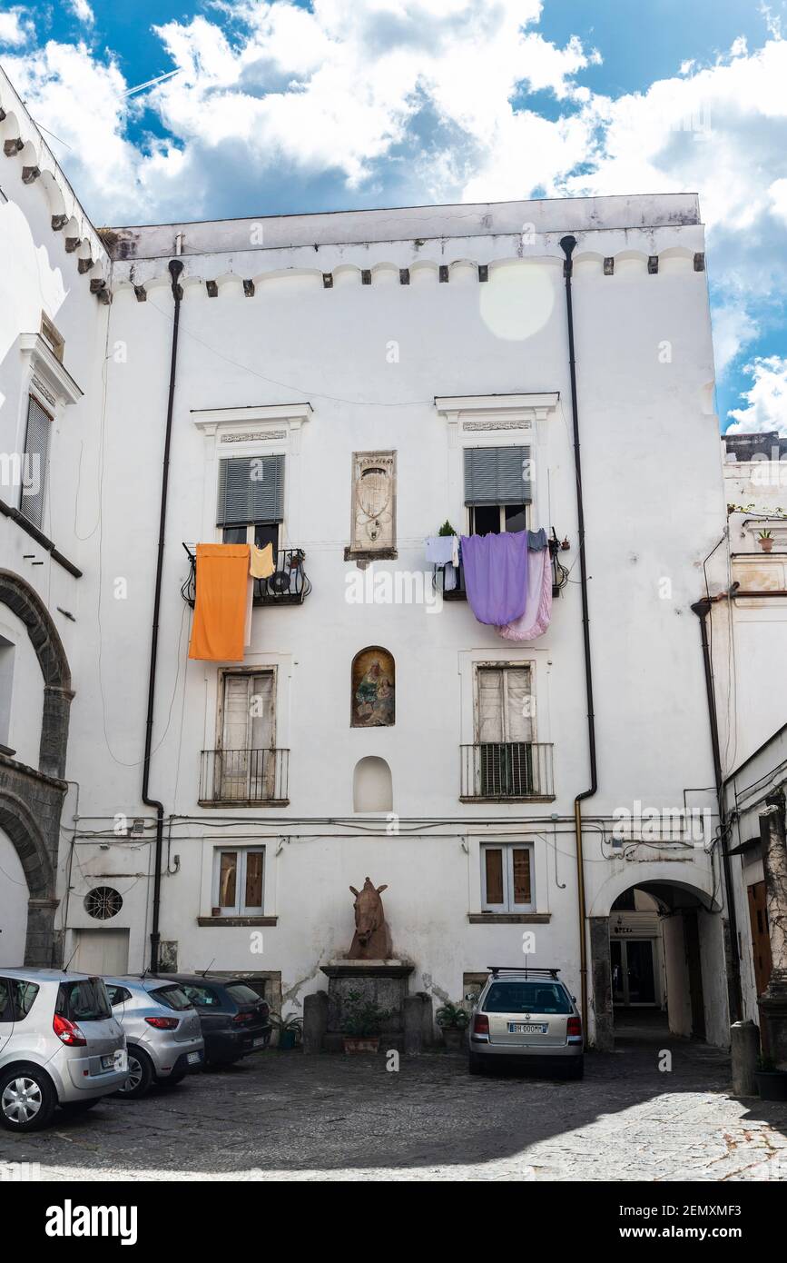 Naples, Italy - September 9, 2019: Patio of classic buildings with cars parked and hanging clothes on the balcony in Naples, Italy Stock Photo