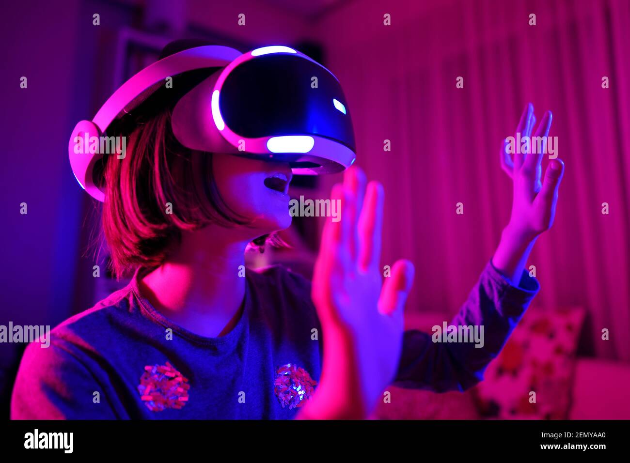 Pretty teenage girl wearing virtual reality headset in a dark room ...