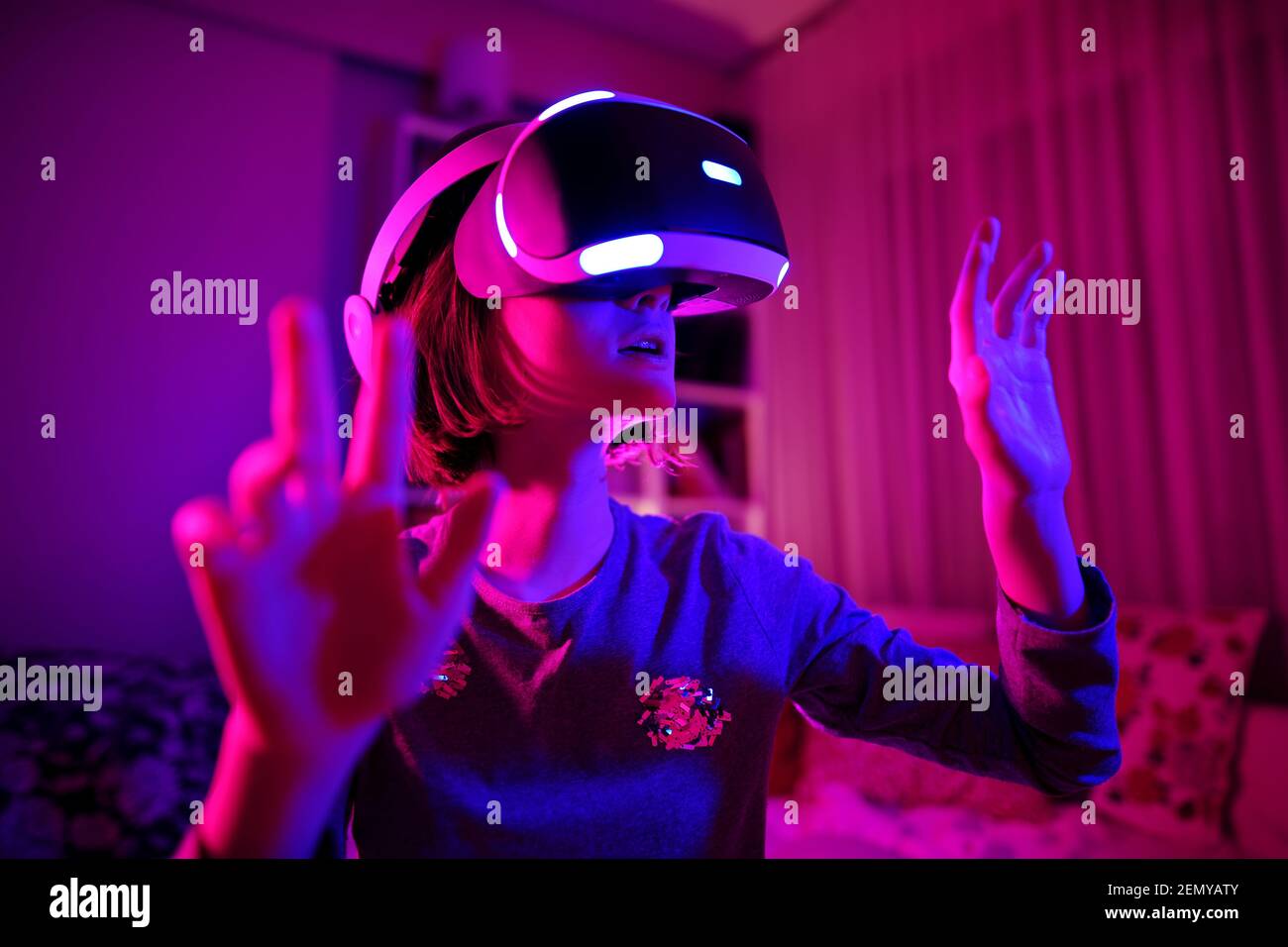 Pretty teenage girl wearing virtual reality headset in a dark room ...