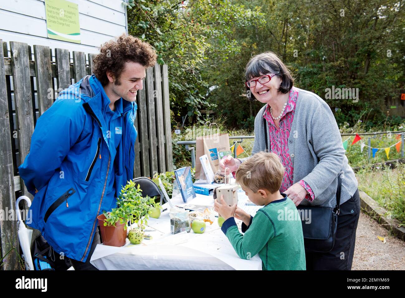 RSPB Stall with man talking to lady and small boy who holds a bird box in his hand, Apple Day Gillespie Ecology Park Stock Photo