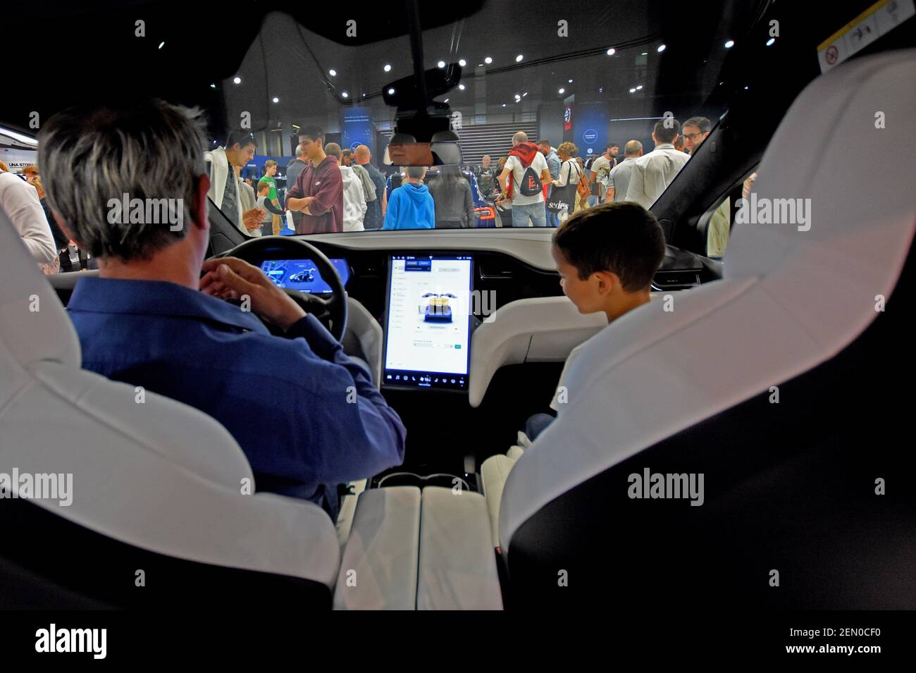 A man and his son examine the interior of an electric vehicle of the ...
