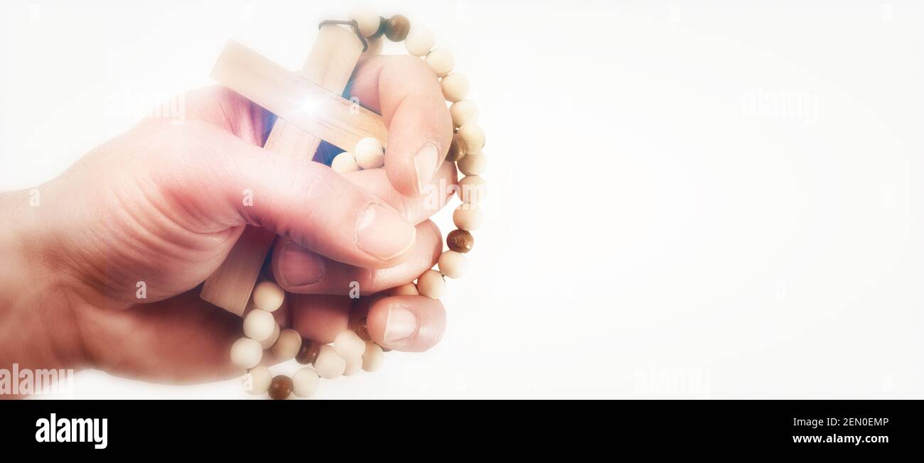 Hand holding with faith a cross with wooden beads to pray with hope with isolated white background Stock Photo