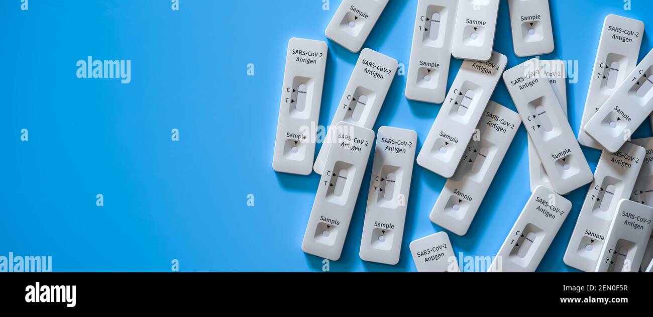 Mass testing for Covid-19 / SARS-CoV-2 infection concept: Several rapid antigen test kits. One kit in the middle showing a positive result (two lines Stock Photo