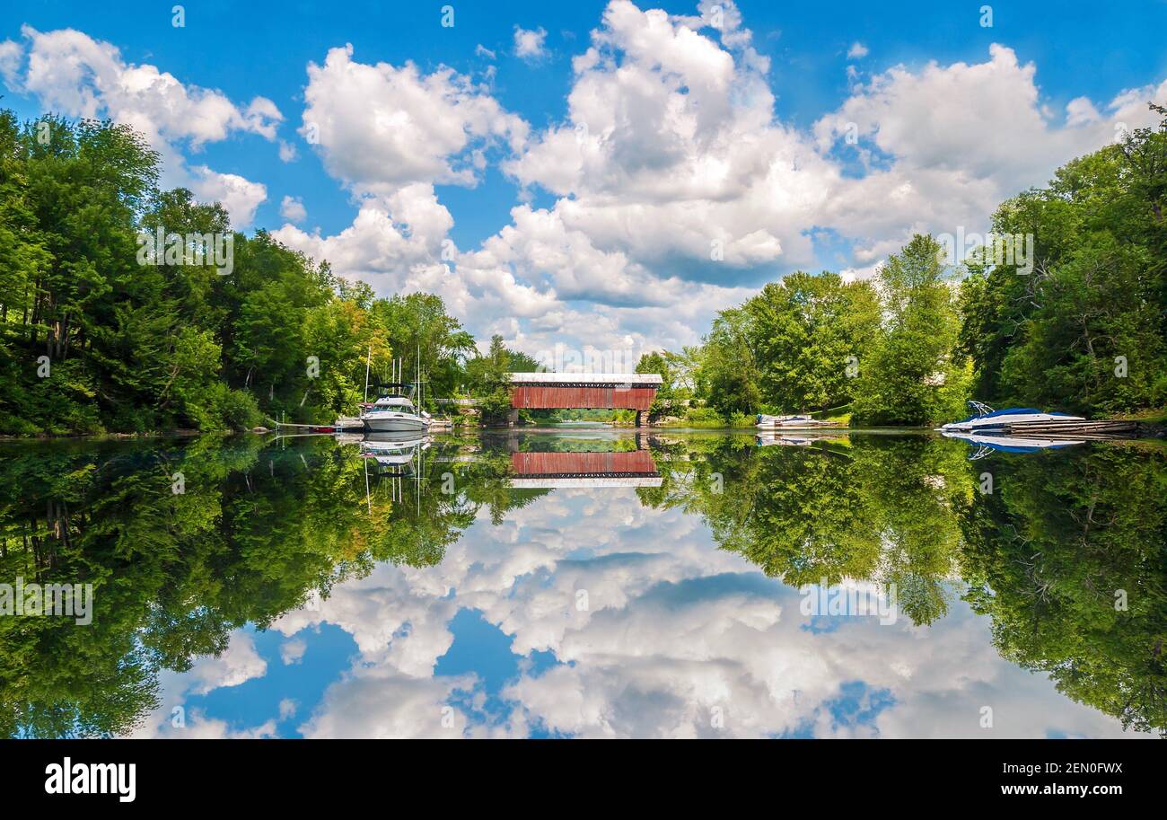 A covered bridge and beautiful reflections on Fitch Bay on Lake Memphremagog in Quebec, Canada. Stock Photo