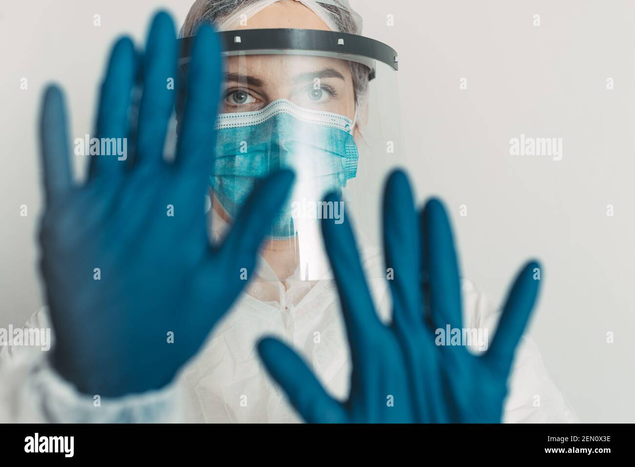 Healthcare worker with shield and mask showing stop gesture Stock Photo