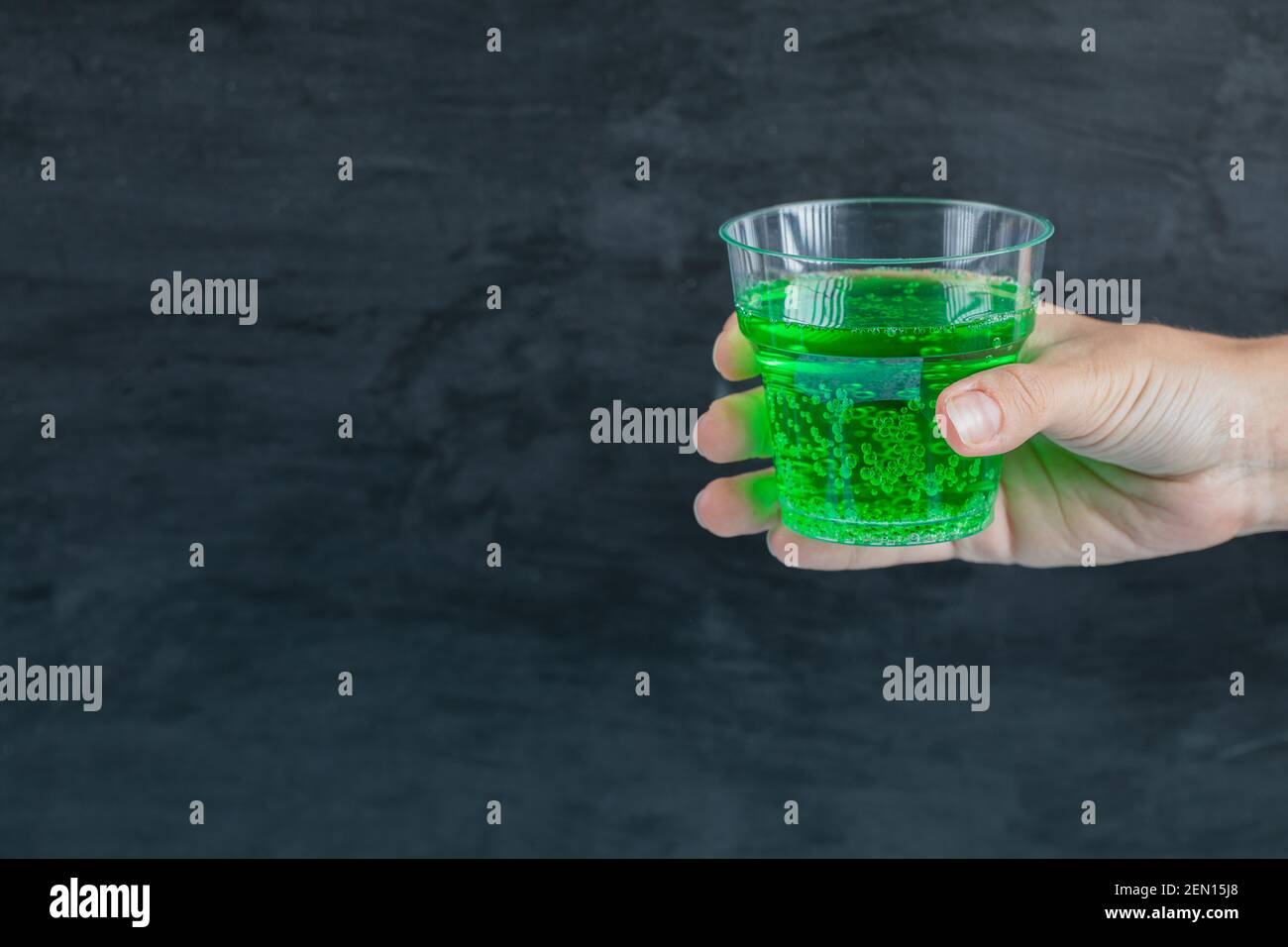 Green drink in the hand with water bubbles inside Stock Photo