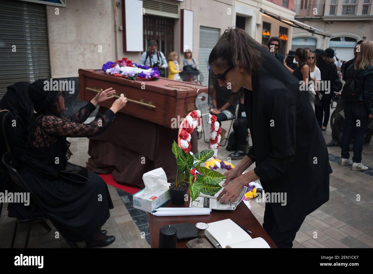 A group of women dressed in mourning clothes are seen crying next to a