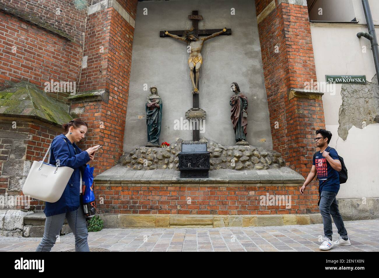 People seen walking past a church wall with a Jesus Christ&rsquo;s 
