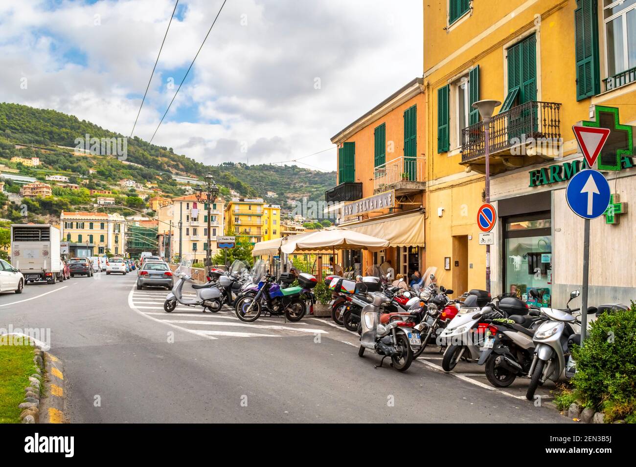 A large number of scooters, motorcycles and motor bikes park outside a neighborhood bar cafe with patio in Ventimiglia, Italy, on the Italian Riviera Stock Photo