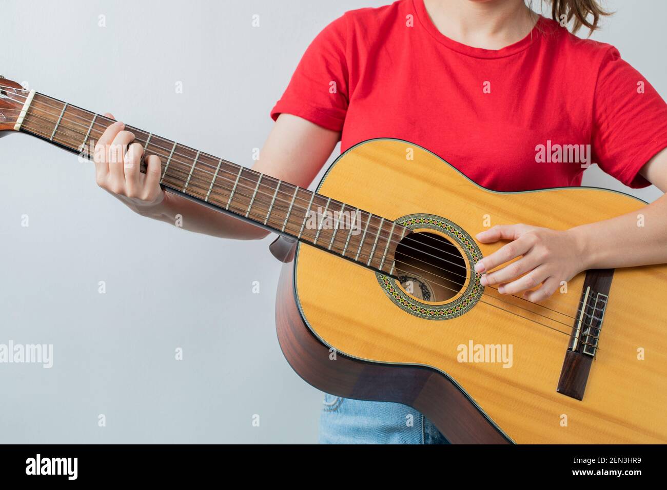 Female model in red shirt holding a wooden guitar Stock Photo - Alamy