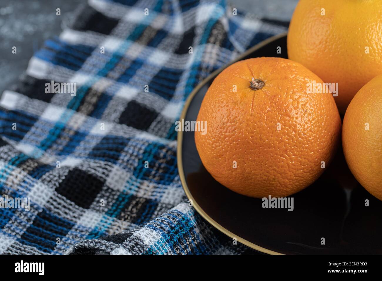 Three ripe oranges on black plate Stock Photo