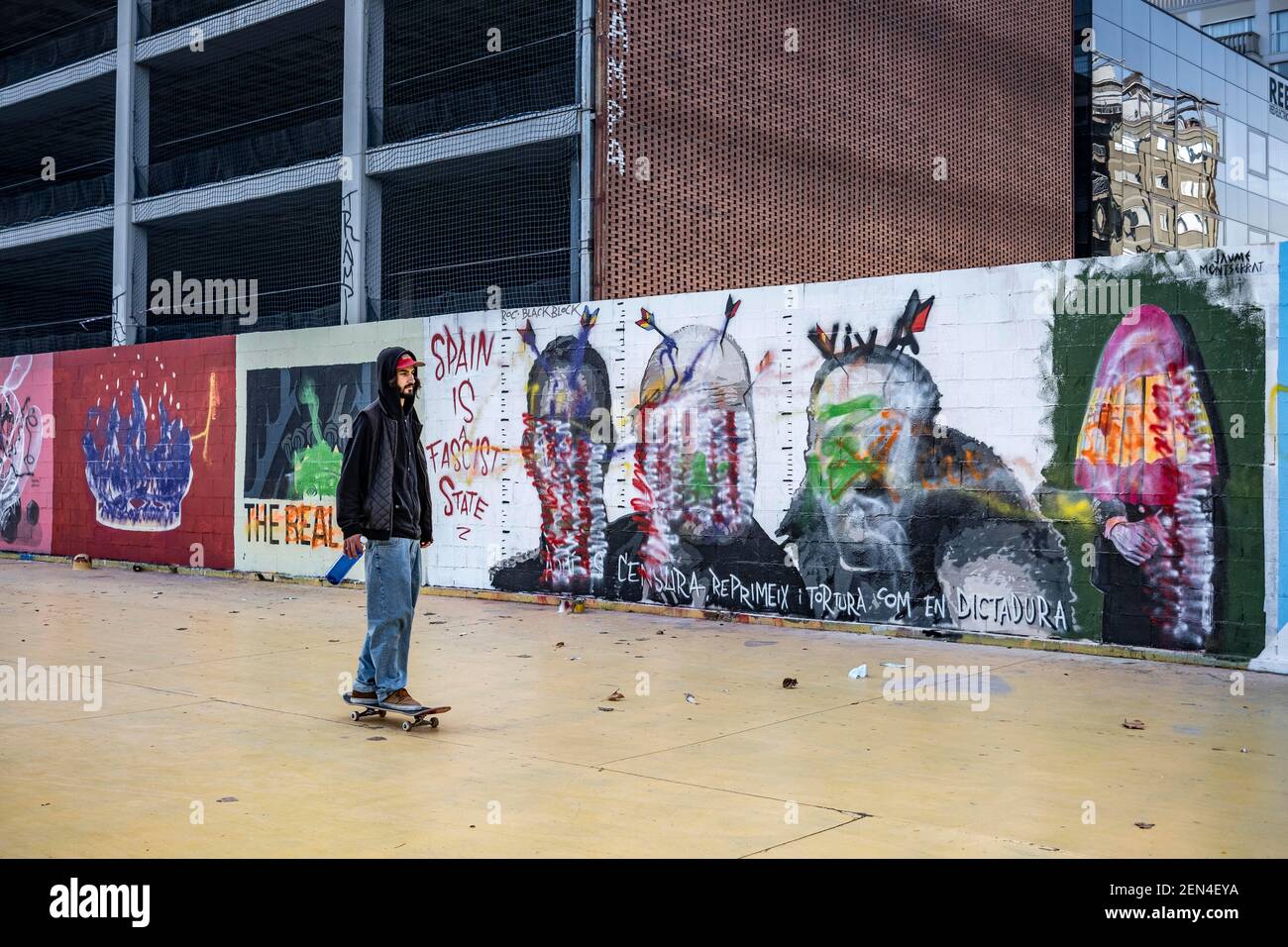 Barcelona, Spain. 25th Feb, 2021. A skater is seen passing in front of the  defaced mural by graffiti artist Rock Black Block painted in the Plaza de  Les Tres Ximeneis.Few days after