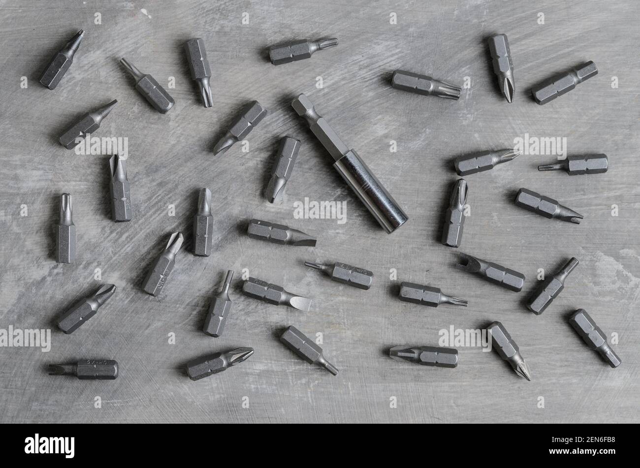 Screwdriver bits for various slots scattered on a gray concrete surface. Stock Photo