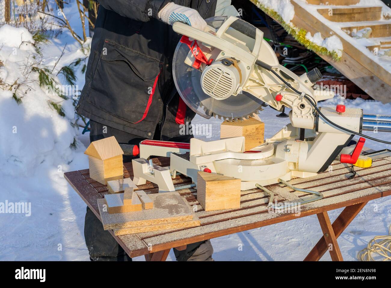 A male worker on the street in winter cuts a block with an angle electric saw with a sharp blade. Stock Photo