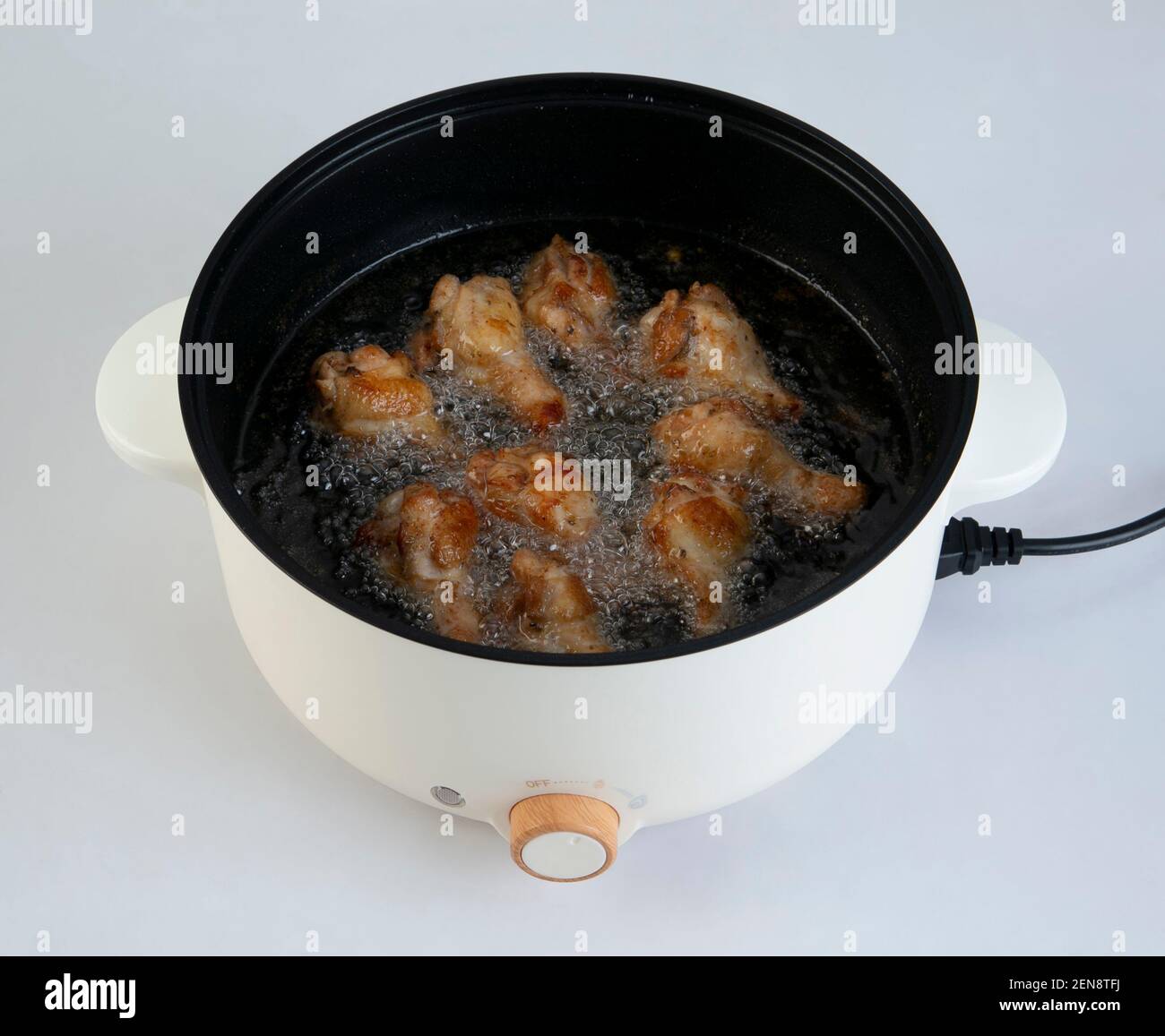 Electric pot of boiling oil with chicken isolated on white background Stock Photo