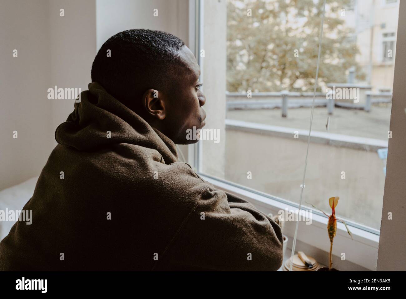 Thoughtful man looking through window at home Stock Photo