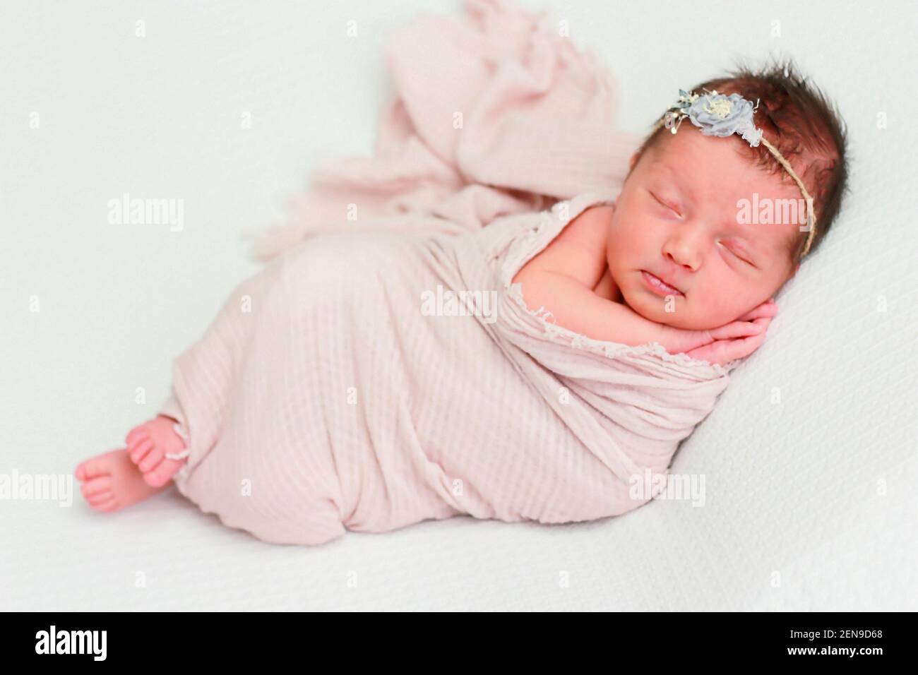 Cute newborn baby girl with a bandage on her head sleeps with her hands