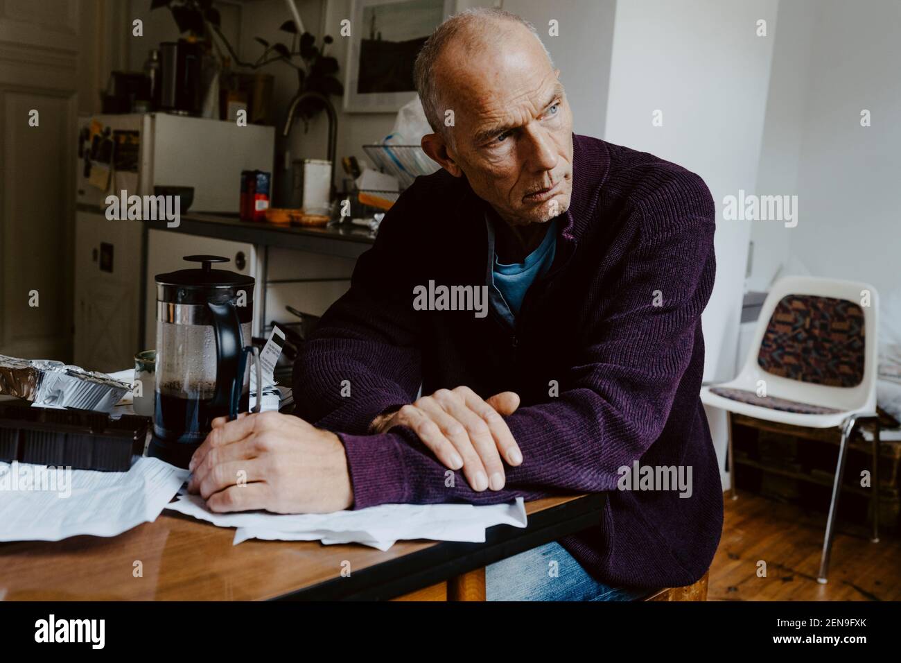Thoughtful man looking away while sitting in living room Stock Photo