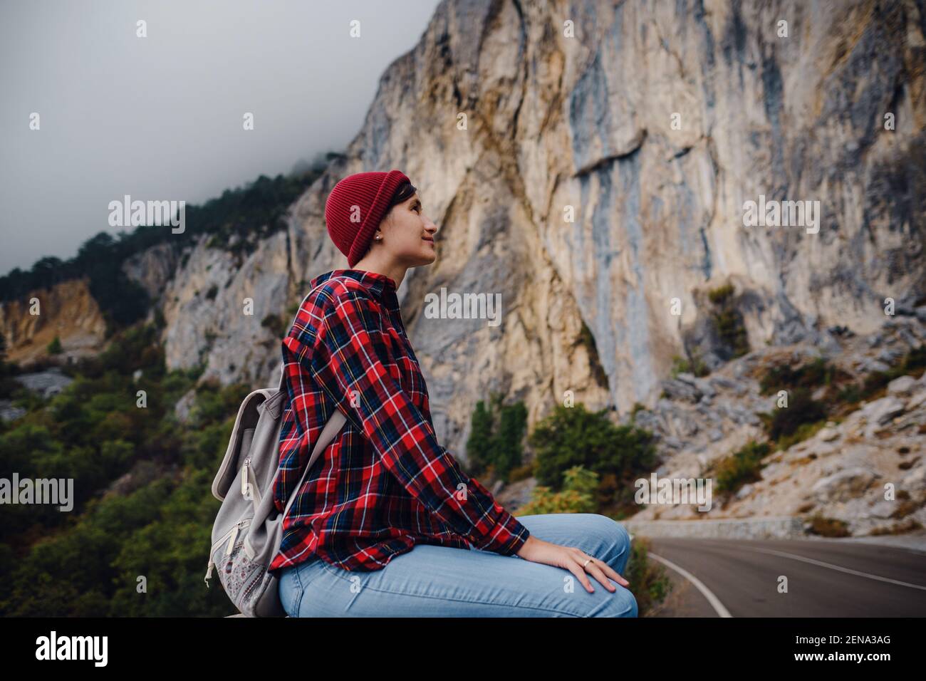 View of Asian hipster woman walking alone on a mountain highway on an autumn ...