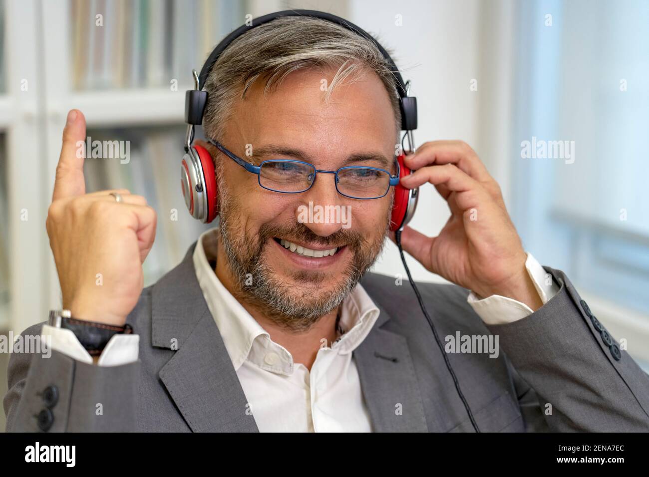 Successful Mature Businessman Sitting at Office Desk Raising Hand in Yes Gesture, Celebrating Business Success. Smiling Excited Businessman Gesturing. Stock Photo
