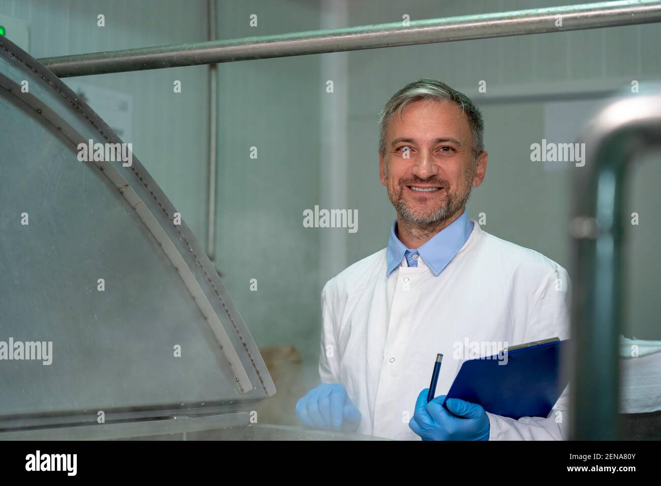 Dairy Plant Technologist With Clipboard Checking the Poduction Process. Stock Photo