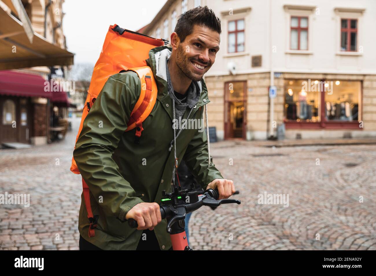 Smiling man with electric push scooter on street in city Stock Photo