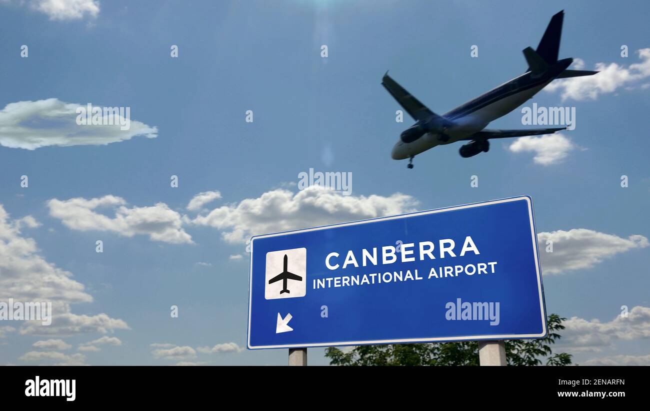 Airplane silhouette landing in Canberra, Australia. City arrival with international airport direction signboard and blue sky in background. Travel, tr Stock Photo