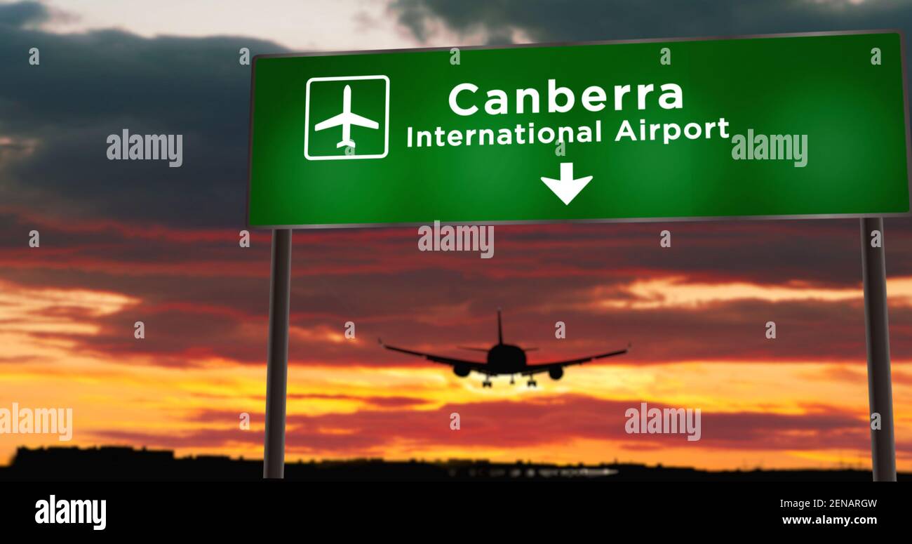 Airplane silhouette landing in Canberra, Australia. City arrival with airport direction signboard and sunset in background. Trip and transportation co Stock Photo