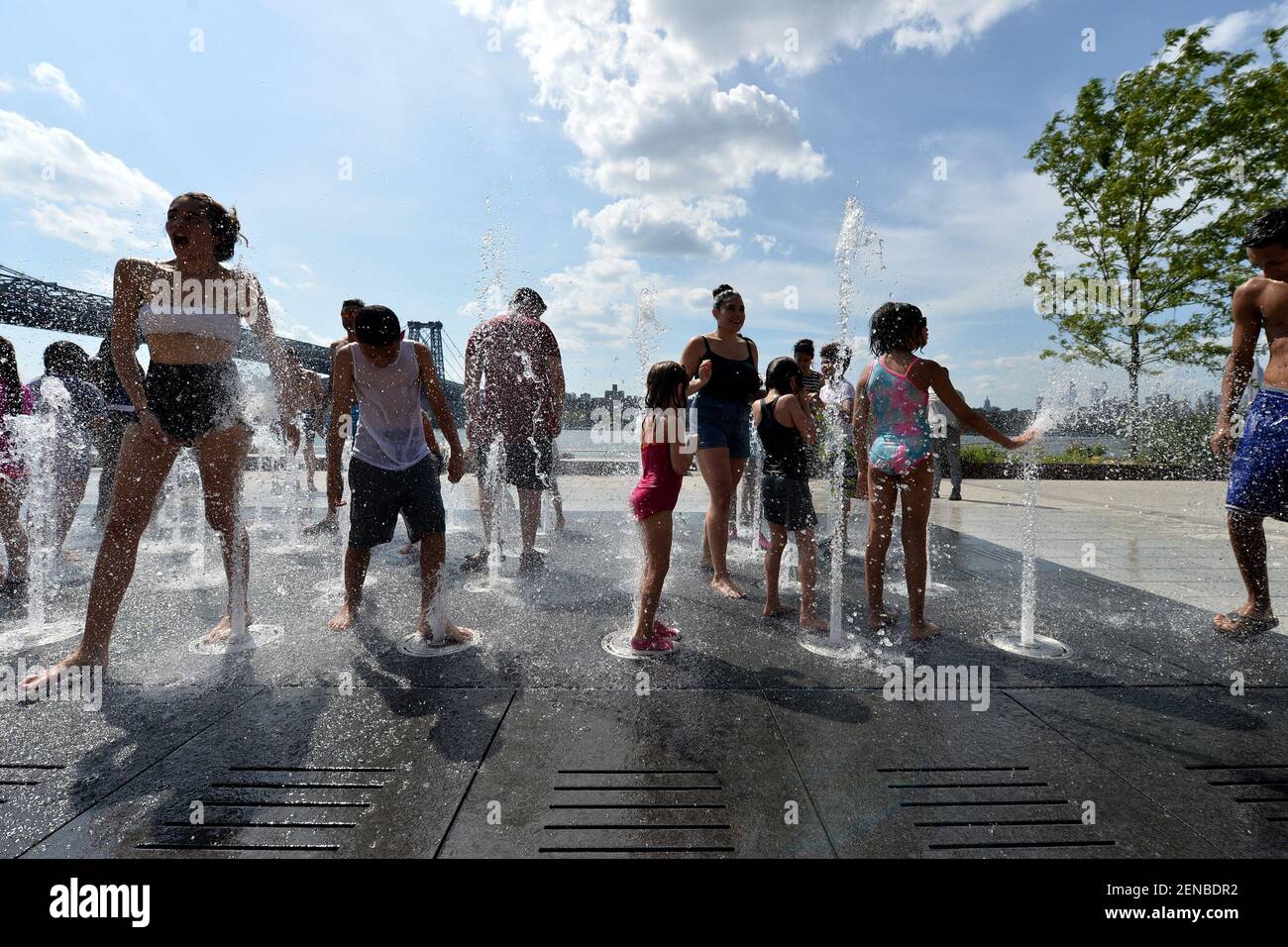 Children and adults play in the Domino Park fountain as temperatures