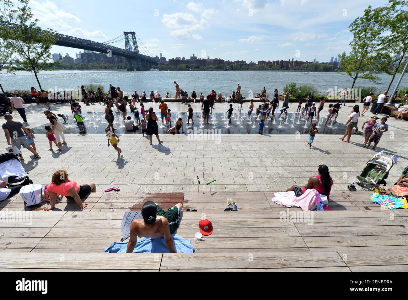 Children and adults play in the Domino Park fountain as temperatures