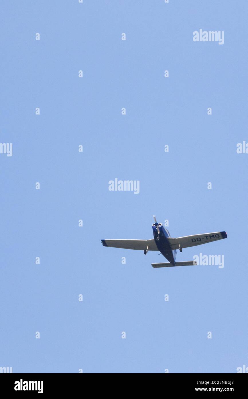 A portrait of a small sport airplane flying through a blue sky. The plane, aircraft is flying straight through the air with its wings level to the gro Stock Photo