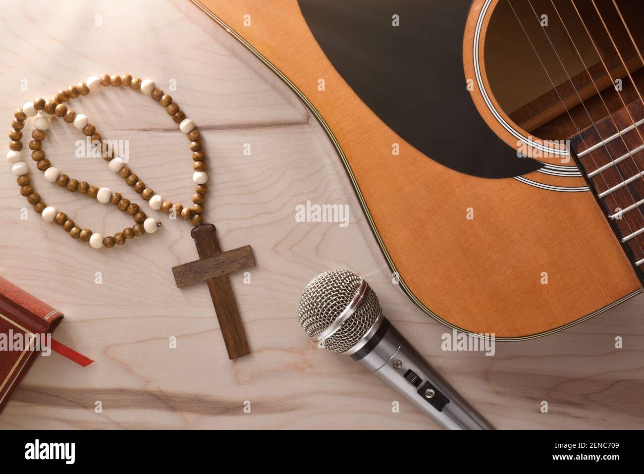 Acoustic guitar and microphone with wooden cross and bible on wooden table close up. Top view. Horizontal composition. Stock Photo