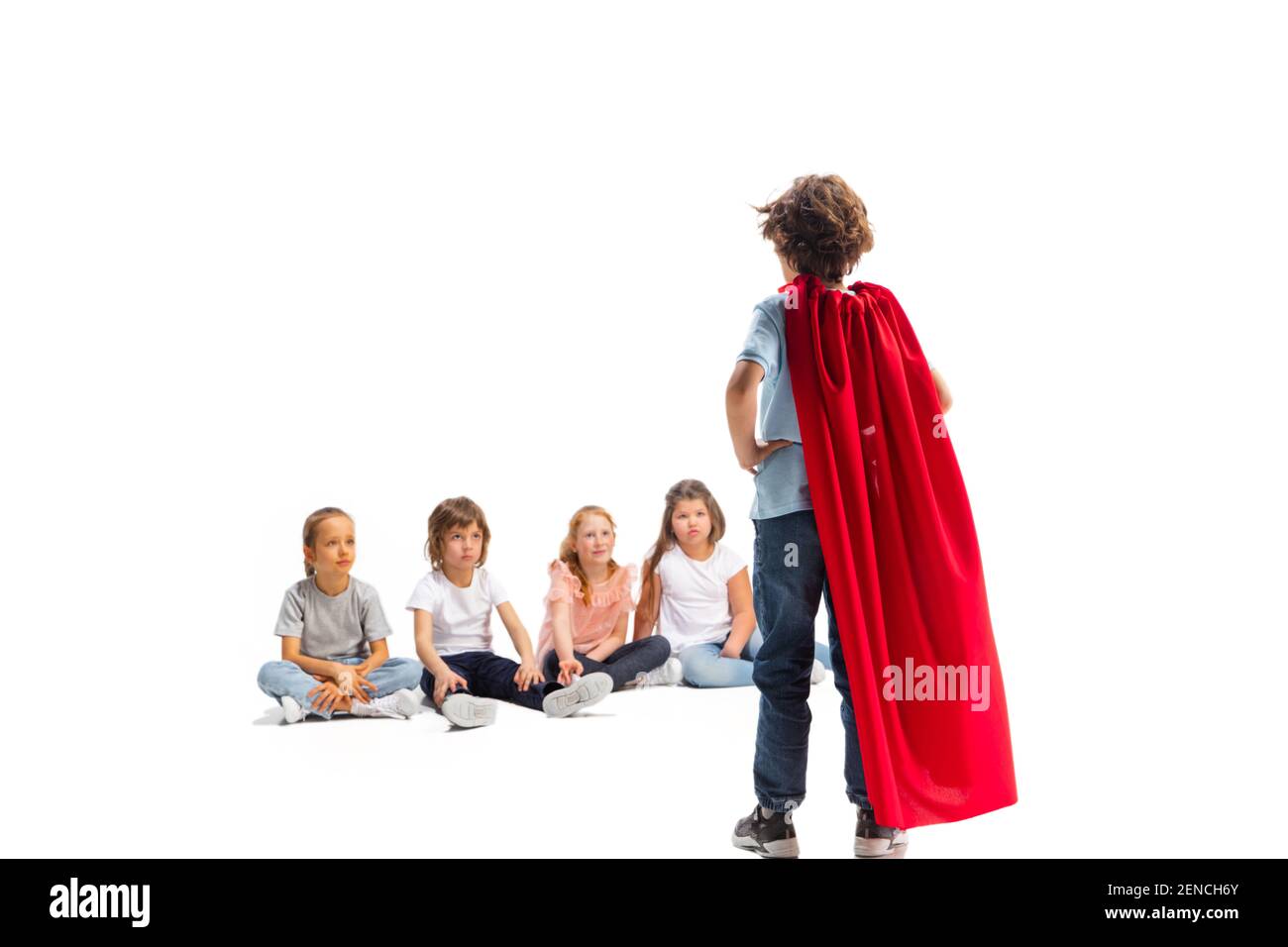 Power. Child pretending to be a superhero with his friends sitting ...
