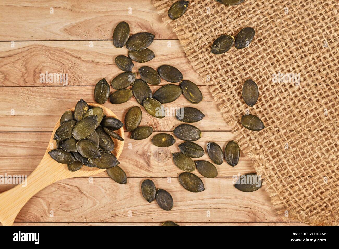 Dark roasted pumpkin seeds without husks on wooden table Stock Photo