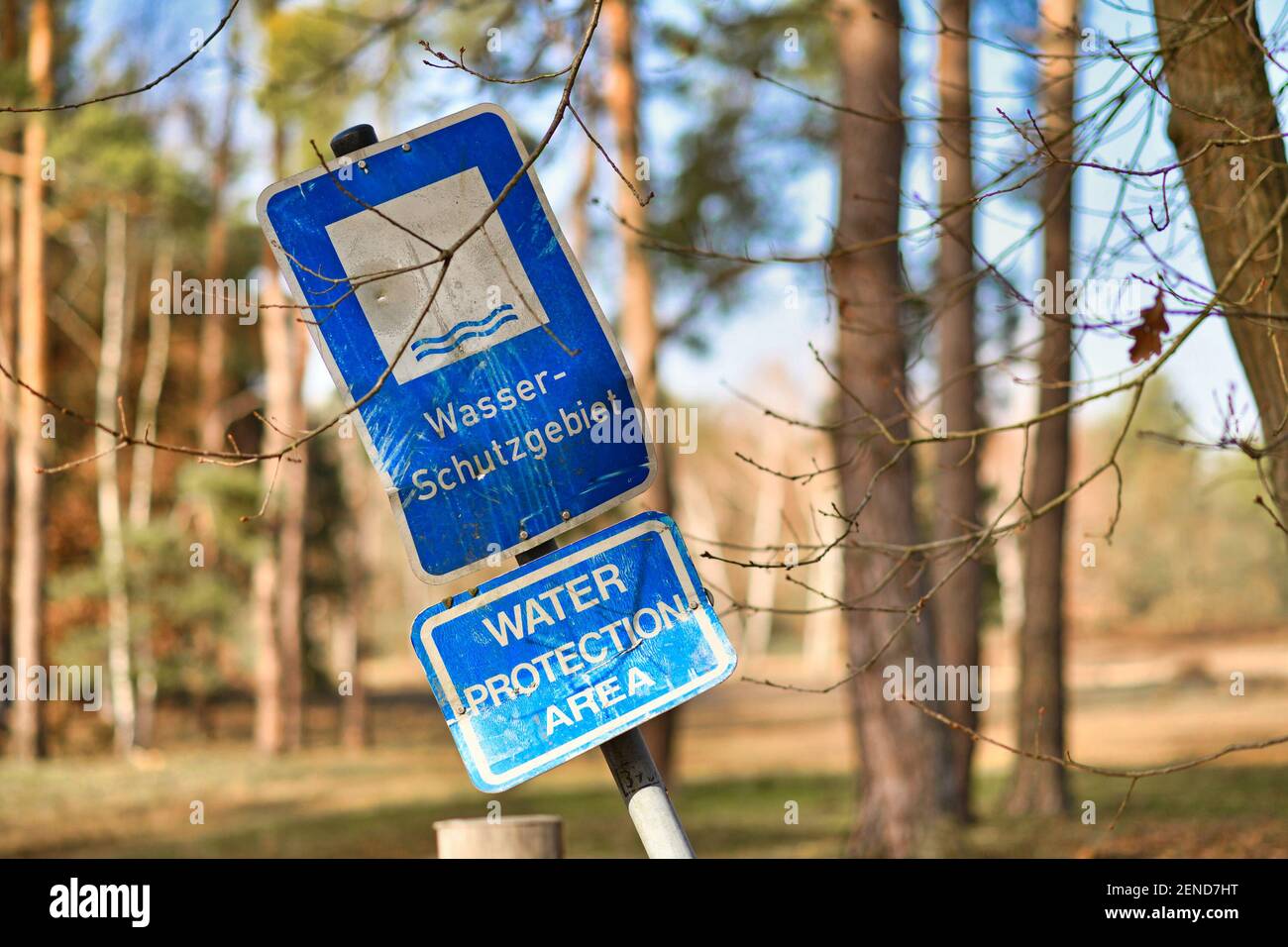 Crooked blue sign with German text 'Water protection area' and English