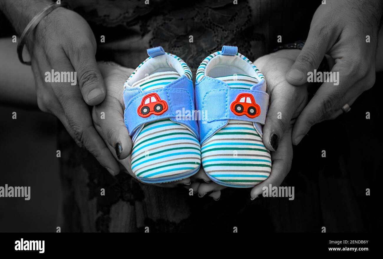 Maternity photo ideas for couple with baby shoes in hand Stock Photo