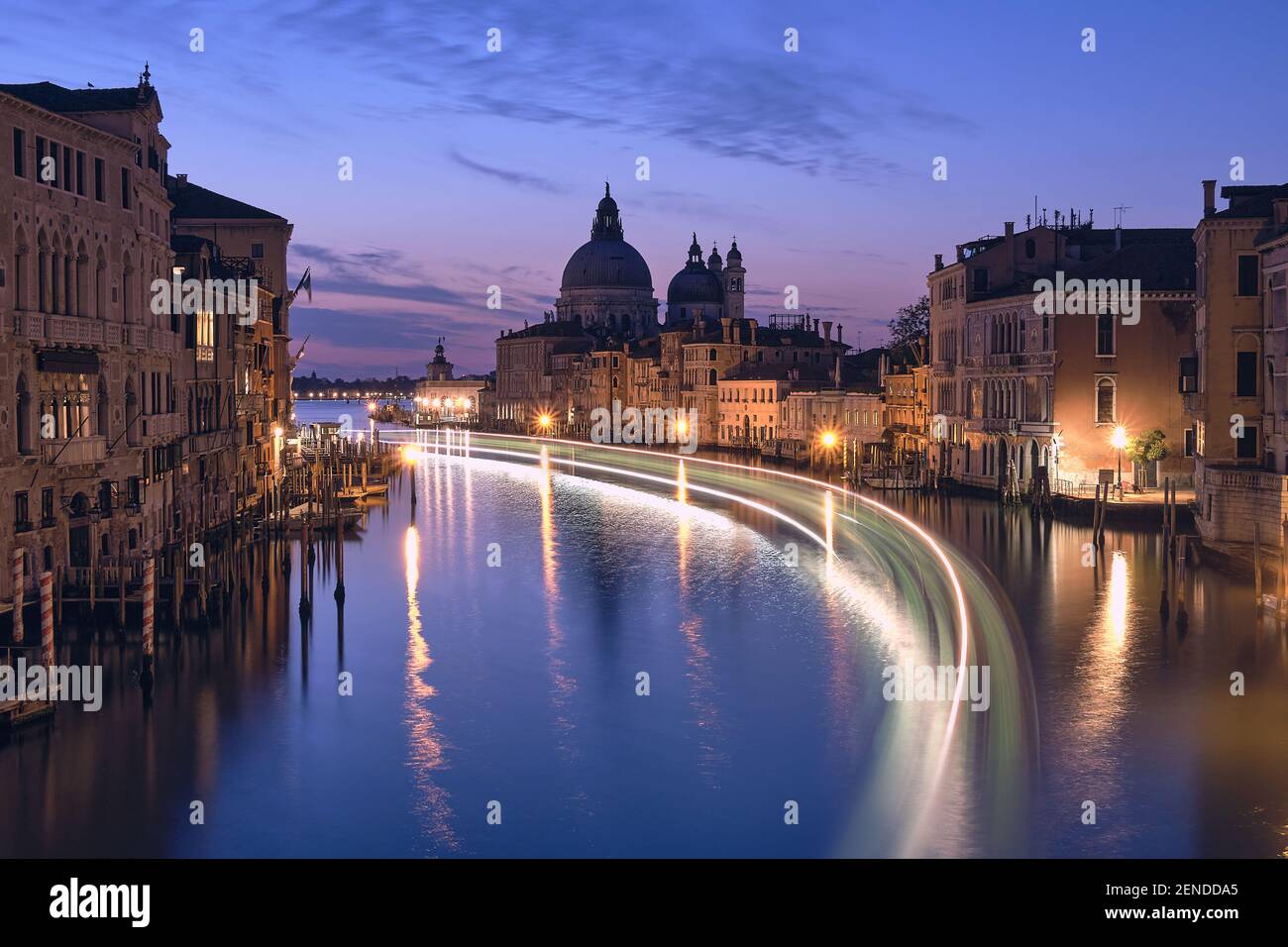 Venice at night. Cityscape image of Grand Canal in Venice, with Santa Maria della Salute Basilica reflected in calm sea. Lights of passenger boat on Stock Photo