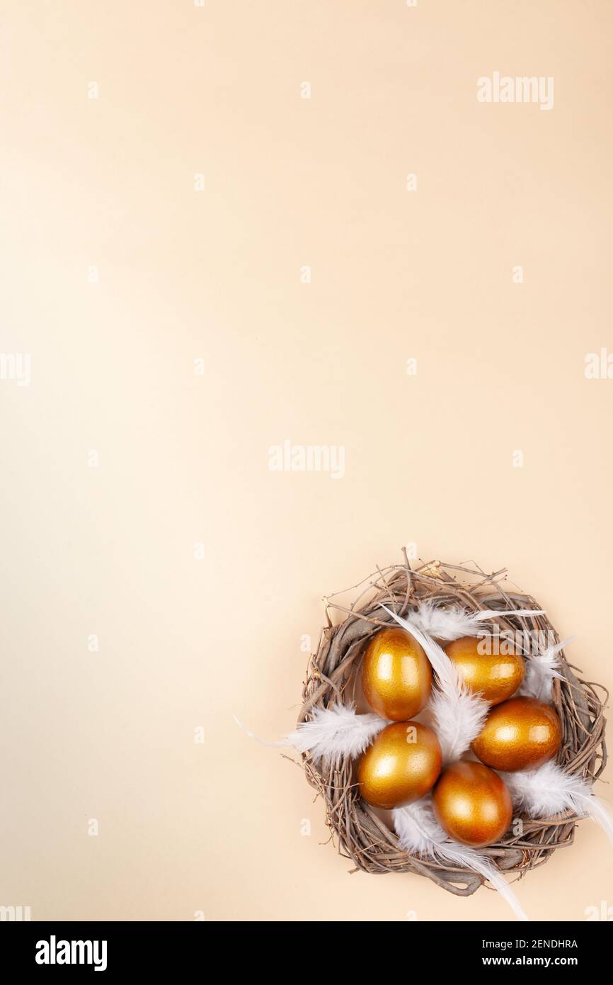 Empty space for text, a banner of happy Easter. Painted golden eggs, white feathers. copy space flat lay top view Vertical nest with eggs Stock Photo