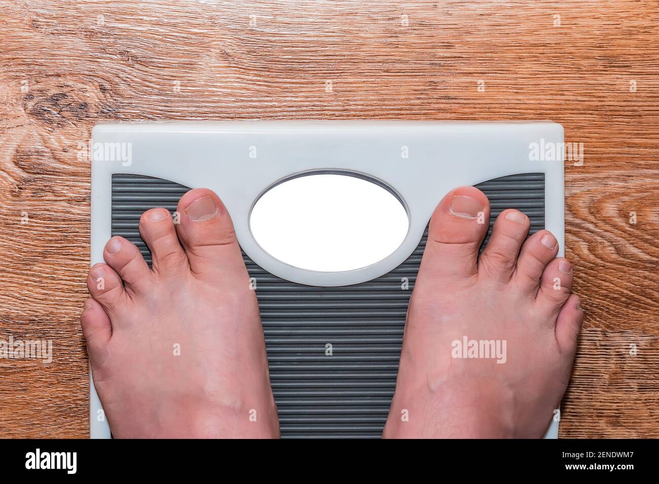 https://c8.alamy.com/comp/2ENDWM7/a-man-stands-barefoot-on-a-floor-scale-and-measures-his-weight-2ENDWM7.jpg