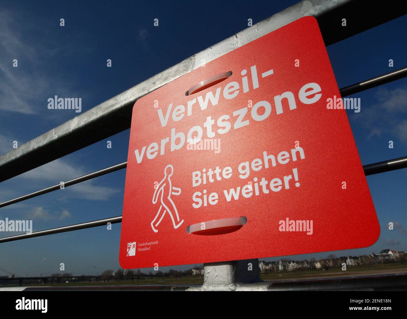 Duesseldorf, Germany. 26th Feb, 2021. A prohibition sign with the  inscription "Verweilverbotszone - Bitte gehen sie weiter" hangs on a grille  on the Rhine promenade. The city of Düsseldorf has imposed a "