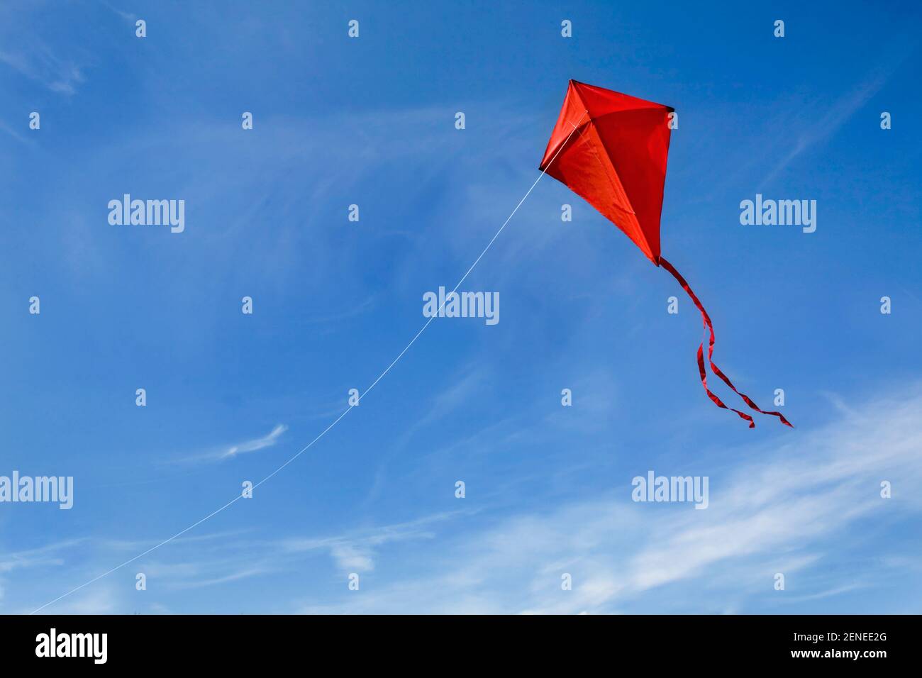 A red kite flying against a blue sky. Stock Photo