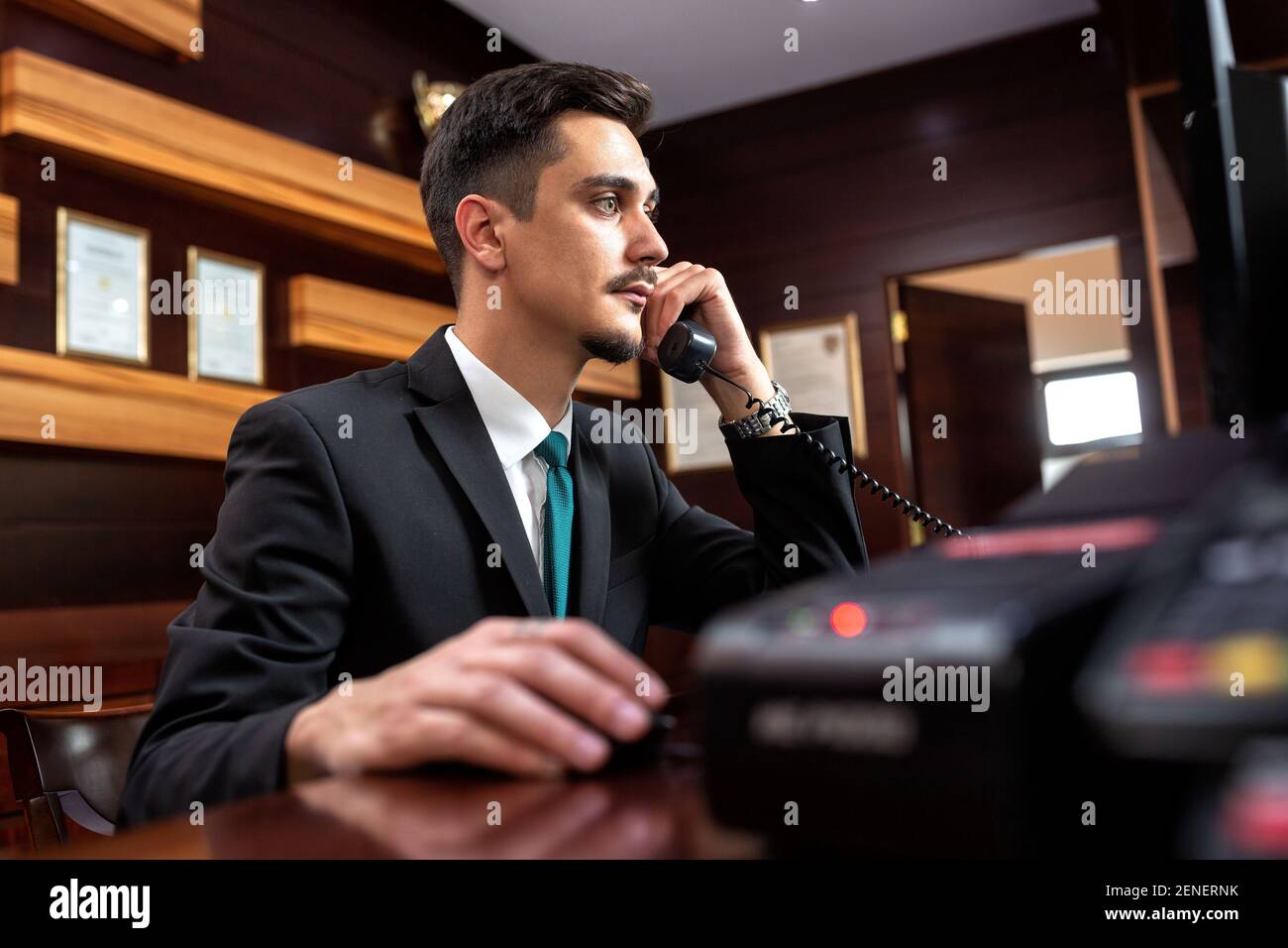 Smooth hotel reception worker talking on the phone, hotel operator Stock Photo
